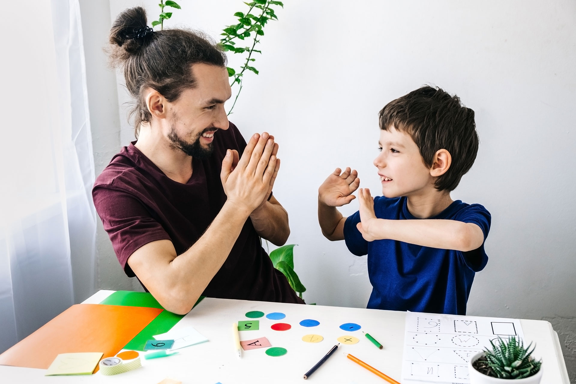 Happy-autism-boy-during-therapy-with-school-counselor,-learning-and-having-fun-together